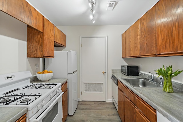 kitchen with white appliances, light countertops, a sink, and light wood finished floors