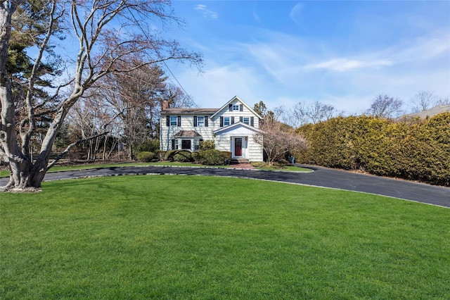 shingle-style home featuring a chimney and a front yard