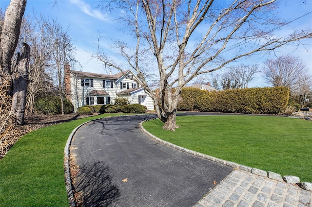 shingle-style home with a front yard and a chimney