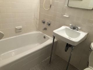 bathroom featuring toilet, shower / washtub combination, and tile walls