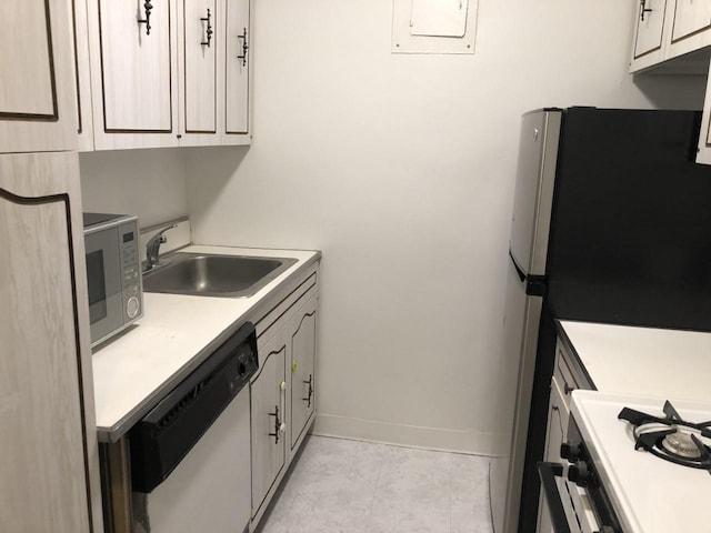 kitchen featuring stainless steel appliances, light countertops, light tile patterned flooring, a sink, and baseboards