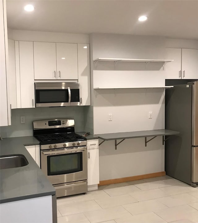 kitchen with recessed lighting, stainless steel appliances, white cabinets, open shelves, and dark countertops