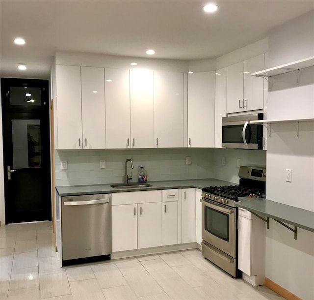 kitchen with dark countertops, white cabinetry, appliances with stainless steel finishes, and a sink