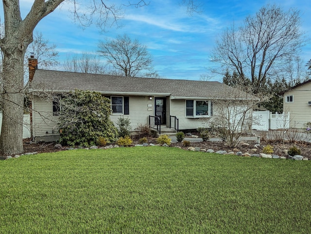 ranch-style house featuring a front yard, roof with shingles, fence, and a chimney