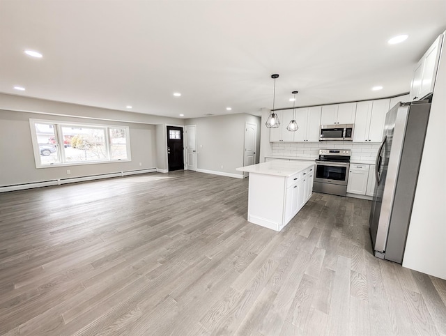 kitchen with stainless steel appliances, open floor plan, baseboard heating, light wood finished floors, and tasteful backsplash