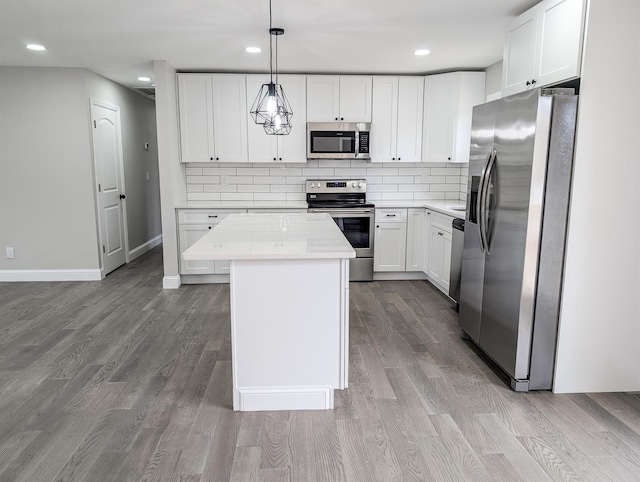 kitchen with wood finished floors, appliances with stainless steel finishes, a kitchen island, and decorative backsplash