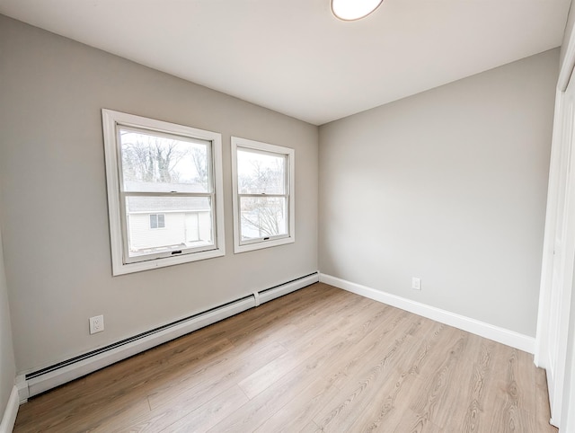 spare room with light wood-style floors, baseboards, and a baseboard heating unit