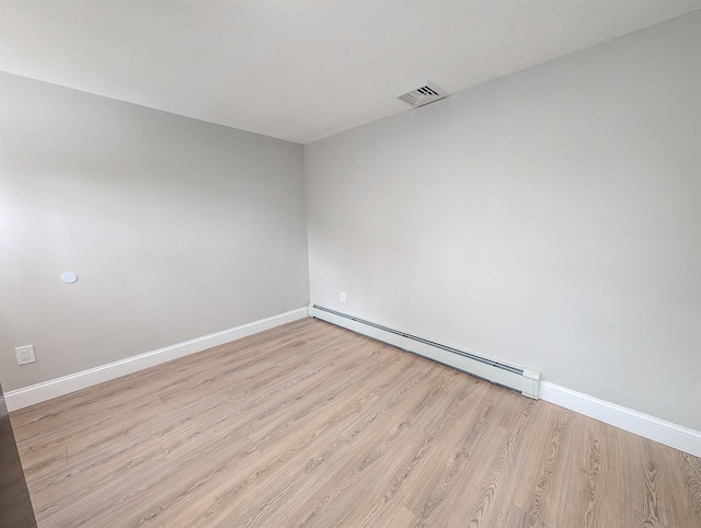 spare room with a baseboard heating unit, light wood-style flooring, visible vents, and baseboards