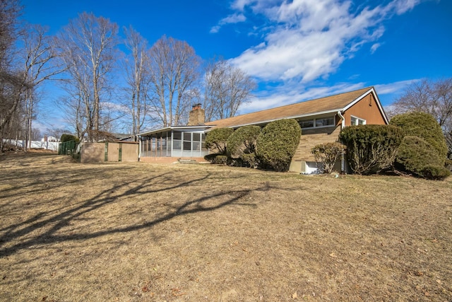 back of house with a lawn, a sunroom, and a chimney