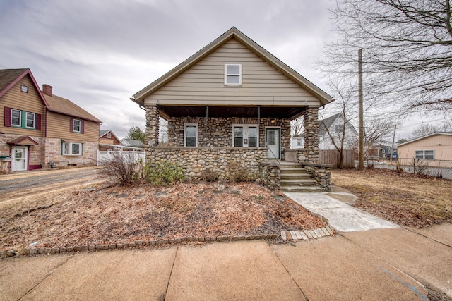 view of front of property with stone siding, fence, and a porch