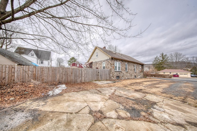 view of side of property featuring stone siding and fence