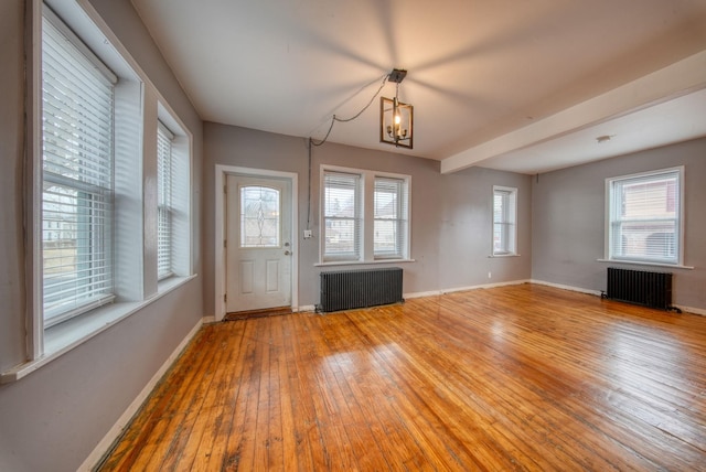 interior space with radiator heating unit, baseboards, wood-type flooring, and a notable chandelier