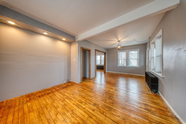 unfurnished living room with beam ceiling, light wood-type flooring, radiator, and baseboards