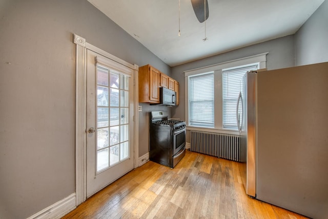 kitchen with appliances with stainless steel finishes, light wood-type flooring, and baseboards