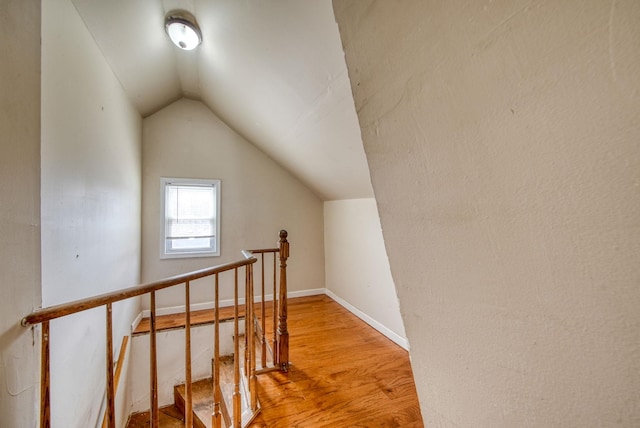 additional living space featuring light wood-type flooring, vaulted ceiling, and baseboards