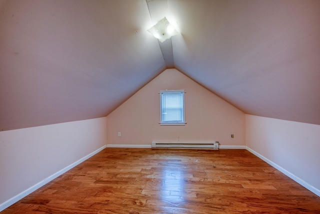 additional living space with vaulted ceiling, baseboard heating, wood finished floors, and baseboards