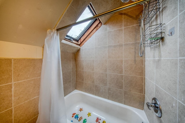 bathroom featuring lofted ceiling with skylight and shower / tub combo with curtain