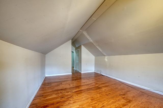 additional living space featuring lofted ceiling, baseboards, and wood finished floors