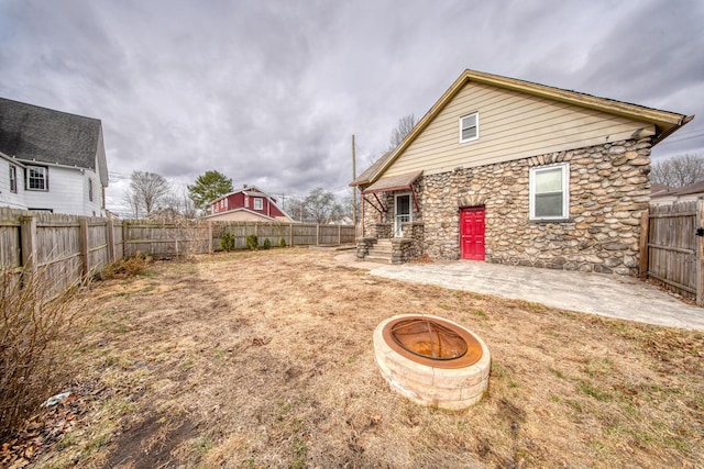 view of yard featuring a fenced backyard, a patio, and a fire pit