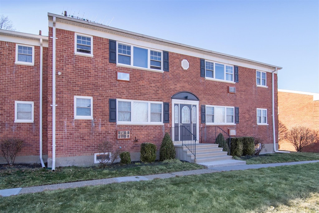 townhome / multi-family property featuring a front lawn and brick siding