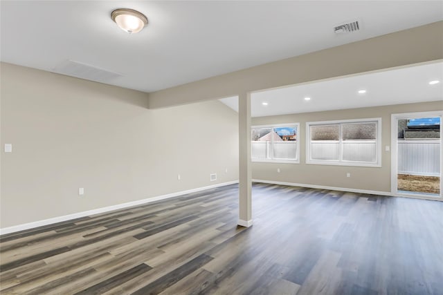 below grade area featuring recessed lighting, dark wood-type flooring, visible vents, baseboards, and plenty of natural light