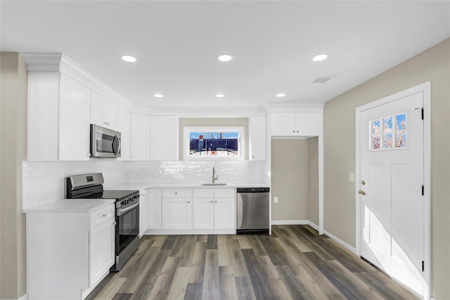 kitchen featuring dark wood-style floors, white cabinetry, appliances with stainless steel finishes, and backsplash