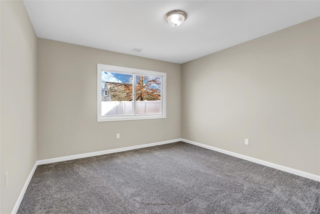 spare room featuring carpet flooring, visible vents, and baseboards