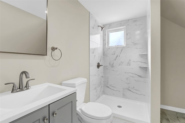 bathroom featuring toilet, baseboards, a tile shower, and vanity