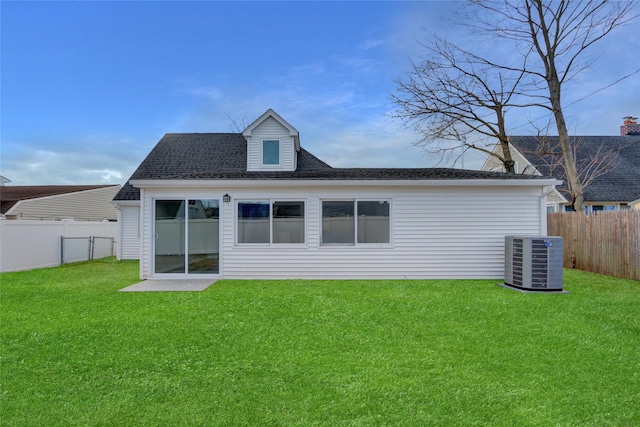 rear view of house featuring central air condition unit, a fenced backyard, roof with shingles, and a yard