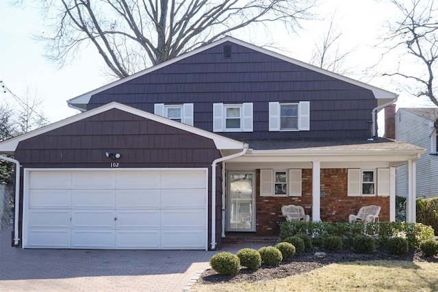 view of front of house featuring an attached garage, a porch, decorative driveway, and brick siding