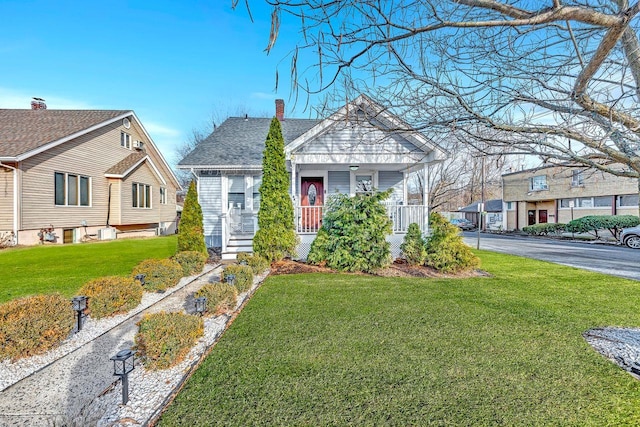 bungalow-style home with a porch, a shingled roof, a chimney, and a front lawn