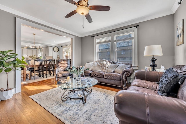 living area with a ceiling fan, crown molding, and light wood-style flooring