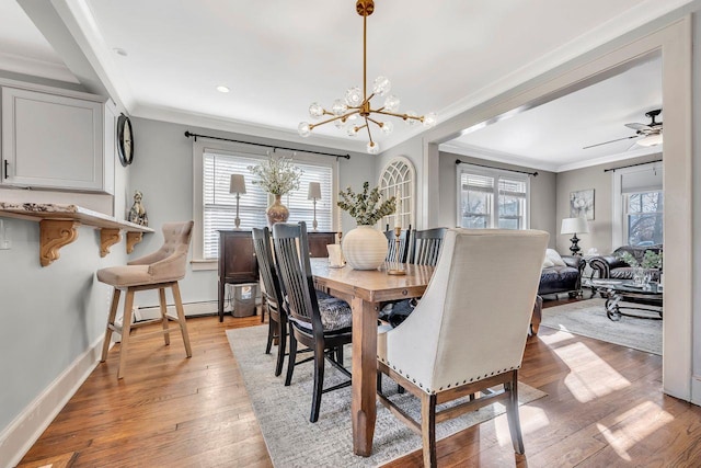 dining space with ornamental molding, light wood-type flooring, baseboards, and ceiling fan with notable chandelier