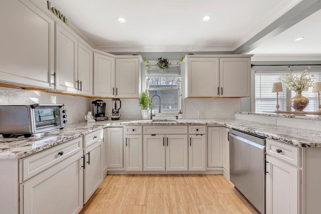 kitchen featuring a toaster, a peninsula, a sink, stainless steel dishwasher, and backsplash