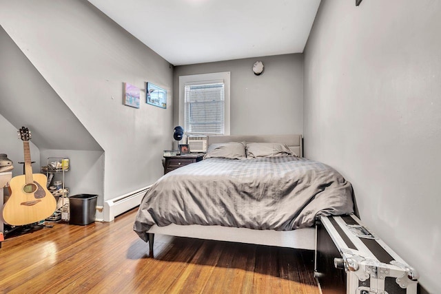 bedroom featuring a baseboard heating unit and wood finished floors