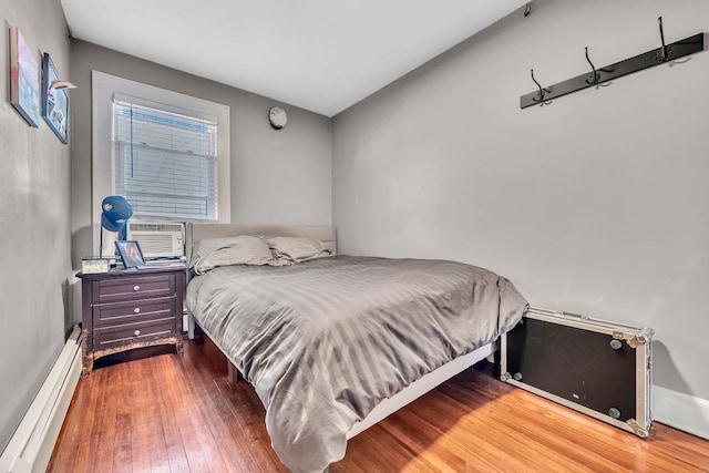 bedroom with hardwood / wood-style flooring, a baseboard heating unit, and cooling unit