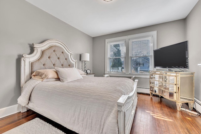 bedroom with a baseboard heating unit, baseboards, and hardwood / wood-style floors