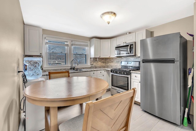 kitchen featuring stainless steel appliances, white cabinets, a sink, and tasteful backsplash