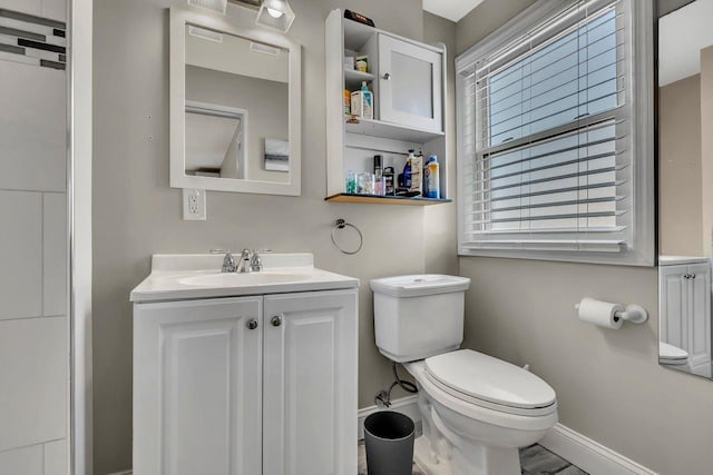 half bathroom featuring vanity, toilet, and baseboards