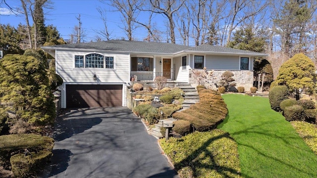 ranch-style home with stairs, an attached garage, covered porch, and driveway