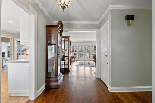 corridor featuring crown molding, baseboards, and wood-type flooring