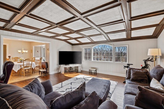 living area featuring a notable chandelier, coffered ceiling, baseboards, and wood finished floors