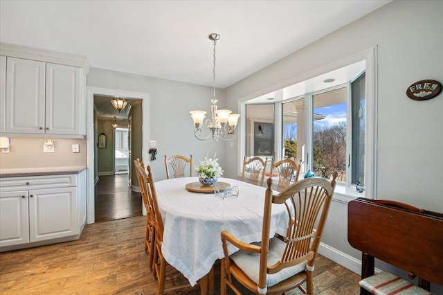 dining space featuring a notable chandelier, light wood-style floors, and baseboards