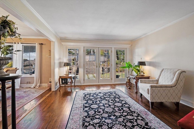 living area with wood finished floors, baseboards, and ornamental molding