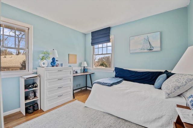 bedroom featuring wood finished floors, visible vents, and baseboards