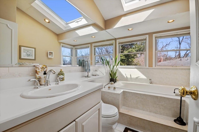 full bathroom featuring lofted ceiling with skylight, a healthy amount of sunlight, vanity, and a garden tub