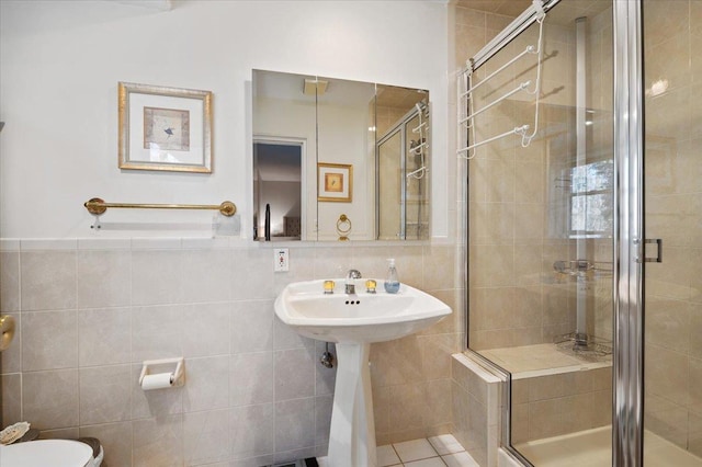 bathroom with tile patterned floors, toilet, tile walls, and a shower stall