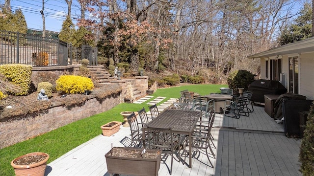 deck with outdoor dining area, a fire pit, a yard, and grilling area