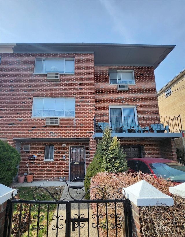 view of front of house featuring brick siding, a fenced front yard, and a balcony