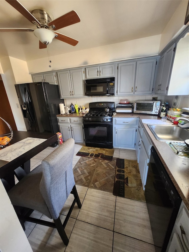 kitchen with tasteful backsplash, ceiling fan, gray cabinetry, black appliances, and a sink